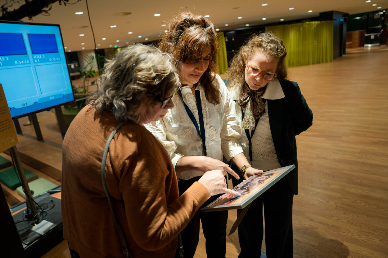 Drie personen bekijken een scherm van een tablet.